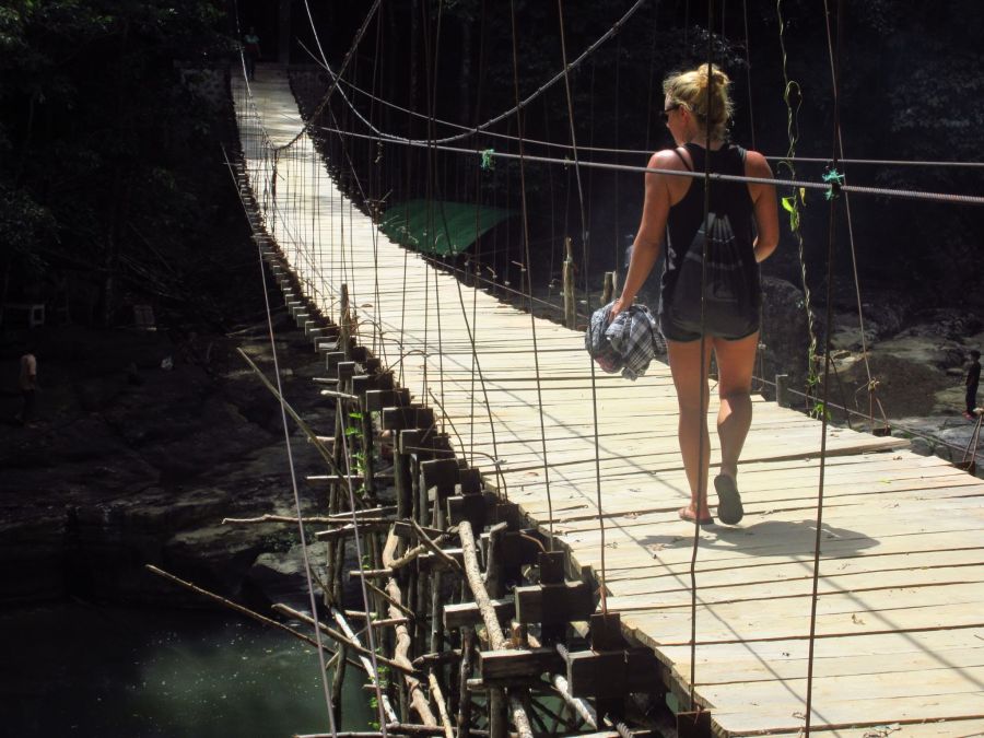 Stimmungsvolle Naturaufnahme. Ein Frau geht im Regenwald über eine Hängebrücke aus Holz. Copyright: echtlebenswert